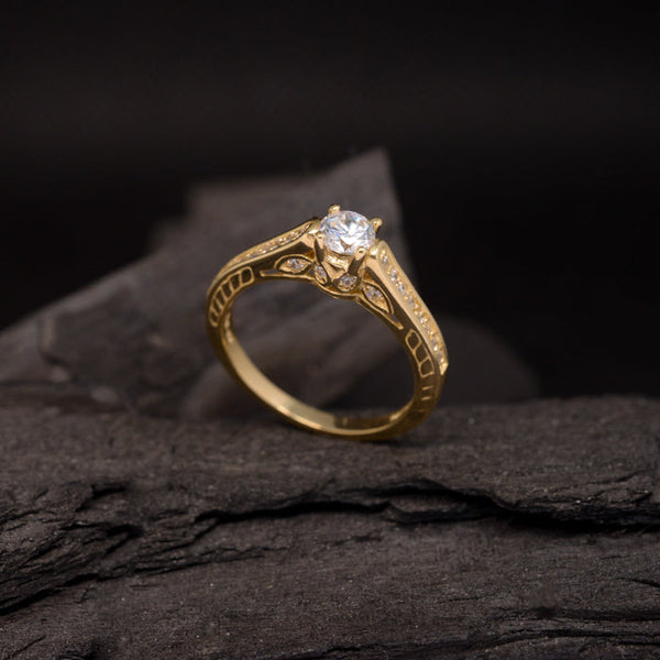 Anillo de compromiso con diamante de laboratorio central de .70ct y cristales laterales elaborado en oro amarillo de 18 kilates