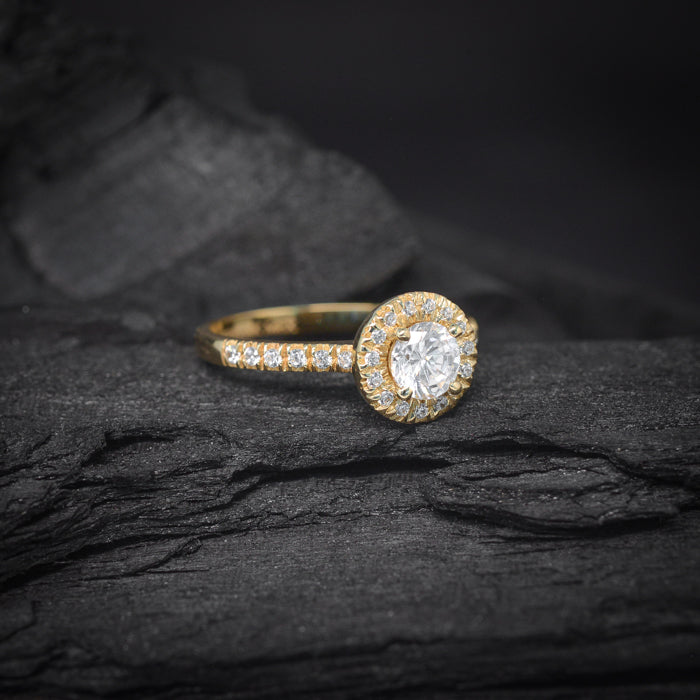 Anillo de compromiso con diamante natural central de .50ct y cristales laterales elaborado en oro amarillo de 14 kilates