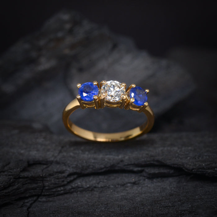 Anillo de compromiso con diamante natural de .50ct y 2 zafiros naturales realizado en oro amarillo de 18 kilates