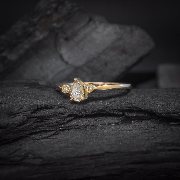 Anillo de compromiso con diamante natural central de .30ct corte gota y 2 diamantes naturales laterales elaborado en oro amarillo de 14 kilates
