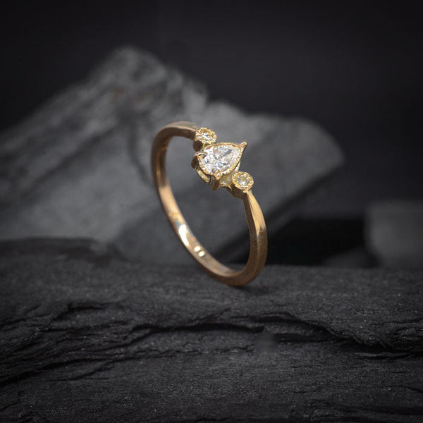 Anillo de compromiso con diamante natural central de .30ct corte gota y 2 diamantes naturales laterales elaborado en oro amarillo de 18 kilates