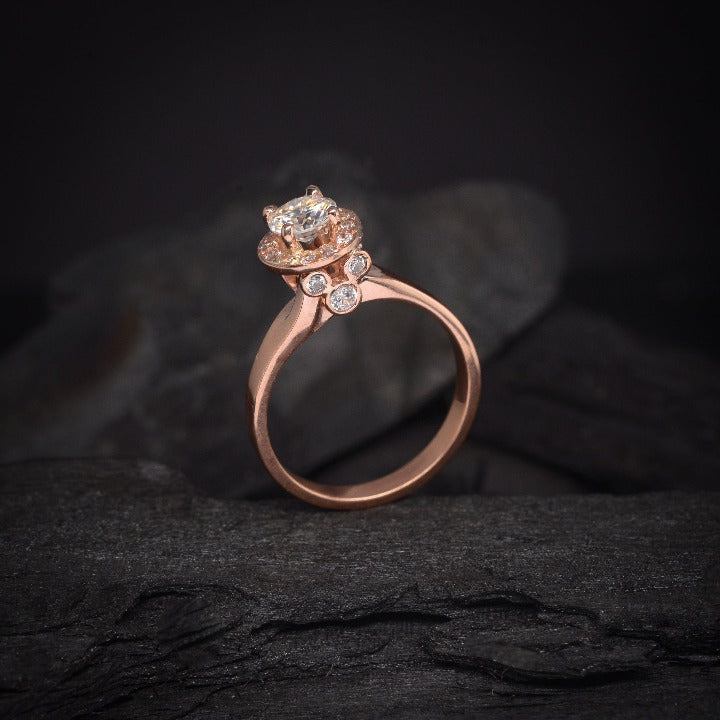 Anillo de compromiso con moissanita de .50ct y cristales laterales elaborado en oro rosa de 14 kilates