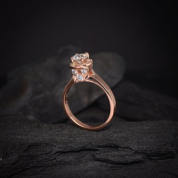 Anillo de compromiso con moissanita de .50ct y cristales laterales elaborado en oro rosa de 14 kilates