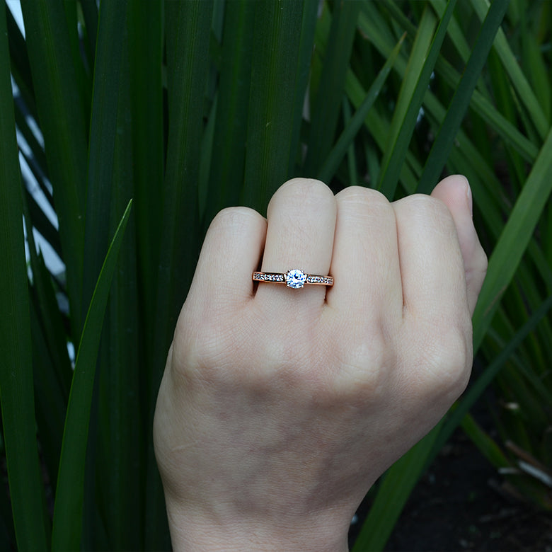 Anillo de compromiso con diamante de laboratorio central de .70ct y cristales laterales elaborado en oro rosa de 18 kilates