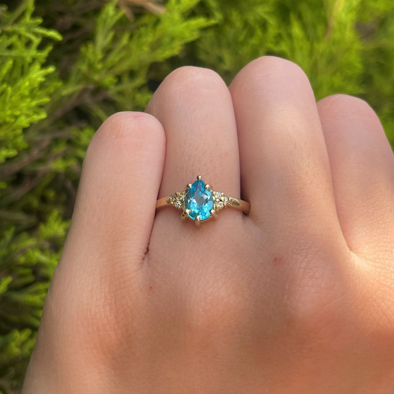 Anillo de compromiso con topacio corte gota y 6 diamantes laterales elaborado en oro amarillo de 14 kilates