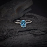 Anillo de compromiso con topacio y cristales laterales elaborado en oro blanco de 14 kilates