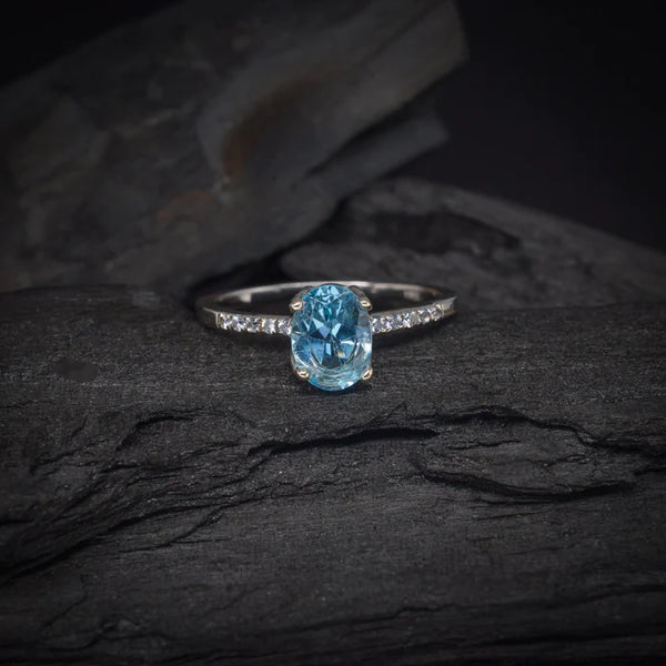 Anillo de compromiso con topacio y cristales laterales elaborado en oro blanco de 14 kilates