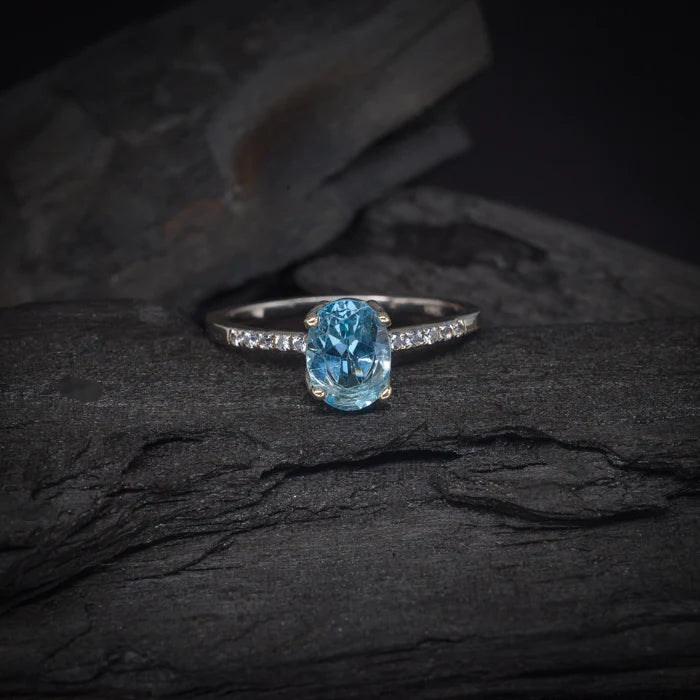Anillo de compromiso con topacio y cristales laterales elaborado en oro blanco de 14 kilates