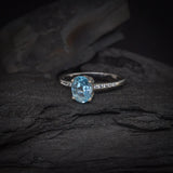 Anillo de compromiso con topacio y cristales laterales elaborado en oro blanco de 14 kilates
