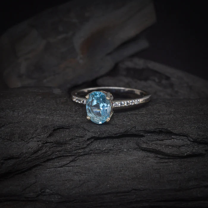 Anillo de compromiso con topacio y cristales laterales elaborado en oro blanco de 14 kilates