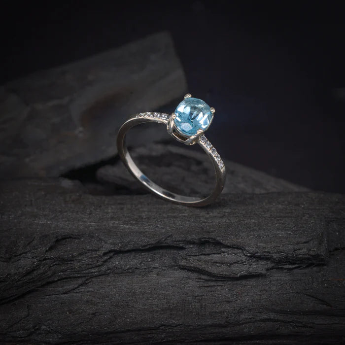 Anillo de compromiso con topacio y cristales laterales elaborado en oro blanco de 14 kilates