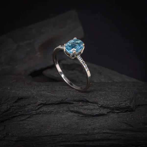 Anillo de compromiso con topacio y cristales laterales elaborado en oro blanco de 14 kilates