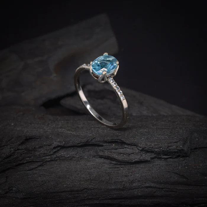 Anillo de compromiso con topacio y cristales laterales elaborado en oro blanco de 14 kilates