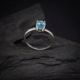 Anillo de compromiso con topacio y cristales laterales elaborado en oro blanco de 14 kilates