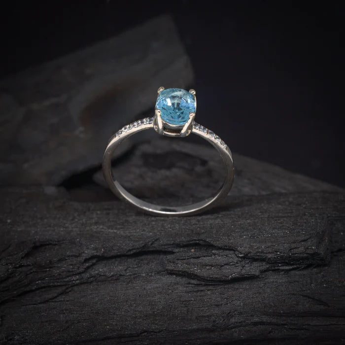 Anillo de compromiso con topacio y cristales laterales elaborado en oro blanco de 14 kilates