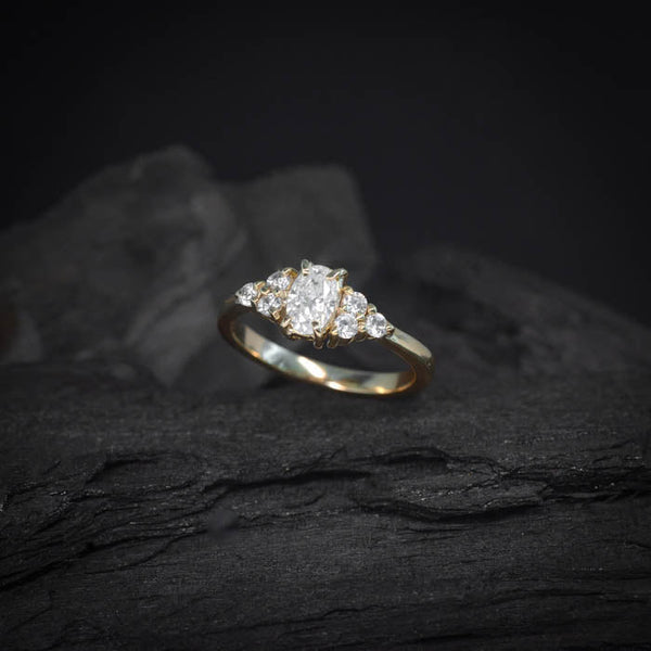Anillo de compromiso con moissanita de .50ct y 6 diamantes laterales realizado en oro amarillo de 18 kilates