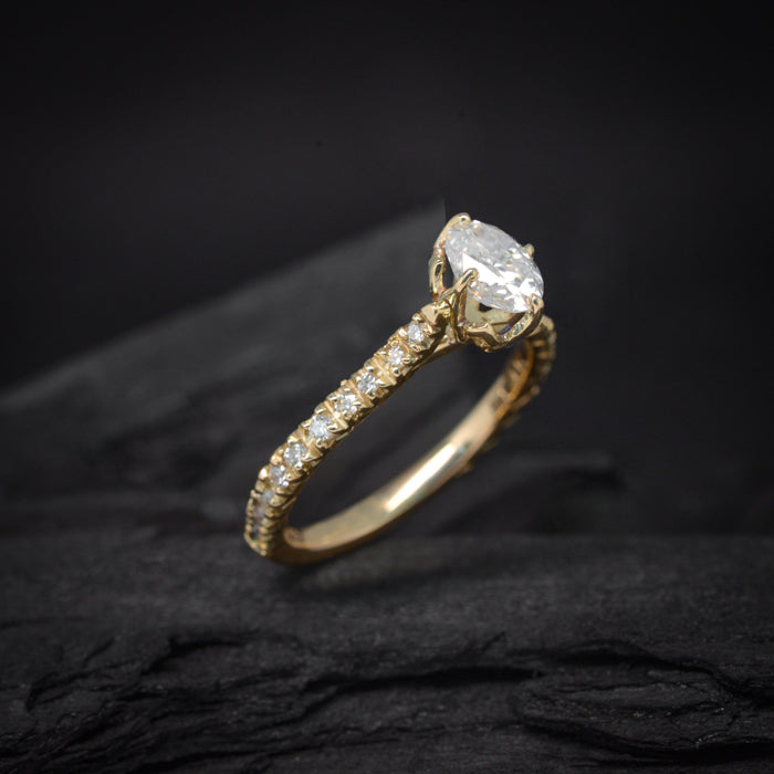 Anillo de compromiso con moissanita de 1.0ct en corte oval, 20 diamantes y 1 zafiro natural realizado en oro amarillo de 14 kilates