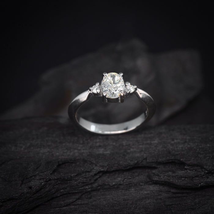 Anillo de compromiso con diamante natural central en corte oval de .60ct con certificación GIA y 2 diamantes naturales laterales elaborado en oro blanco de 18 kilates
