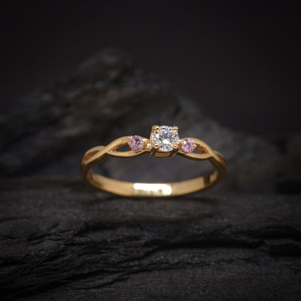 Anillo de compromiso con diamante natural de .20ct y 2 zafiros rosa laterales elaborado en oro amarillo de 14 kilates