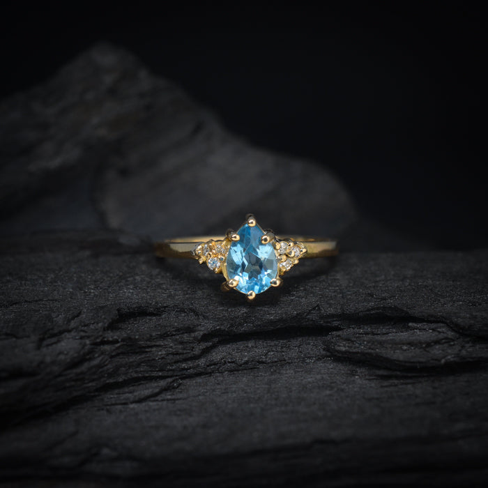 Anillo de compromiso con topacio corte gota y 6 diamantes laterales elaborado en oro amarillo de 14 kilates
