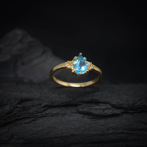 Anillo de compromiso con topacio corte gota y 6 diamantes laterales elaborado en oro amarillo de 14 kilates
