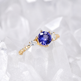 Anillo de compromiso con tanzanita natural de .80ct corte brillante y 12 moissanitas laterales elaborado en oro amarillo de 14k