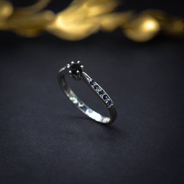 Anillo de compromiso con diamante negro y zafiros elaborado en oro blanco de 14 kilates