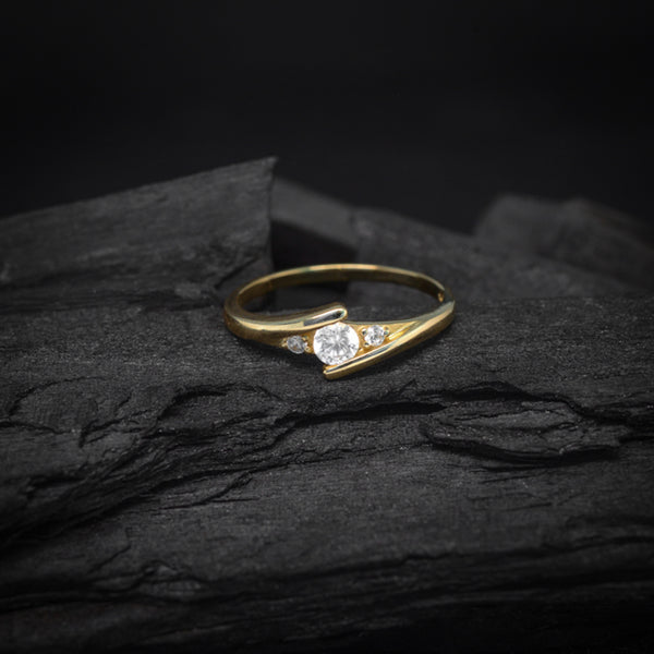 Anillo de compromiso con moissanita de .20ct y 2 diamantes naturales laterales elaborado en oro amarillo de 14 kilates