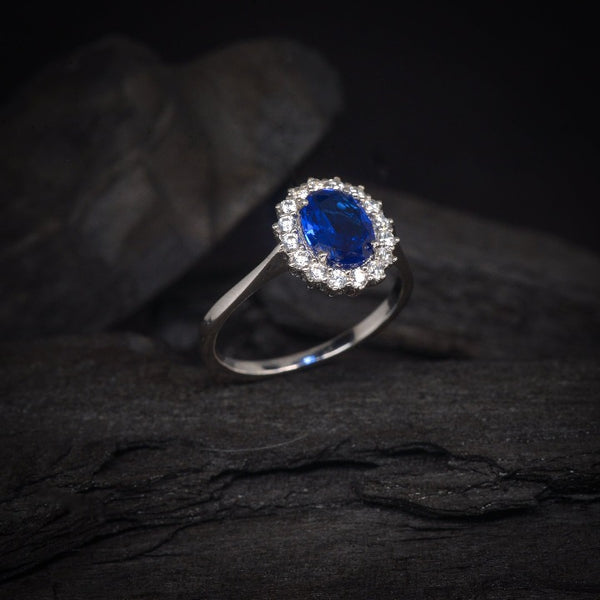 Anillo de compromiso con cristal azul y cristales laterales elaborado en oro blanco de 14 kilates