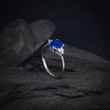Anillo de compromiso con cristal azul y cristales laterales elaborado en oro blanco de 14 kilates