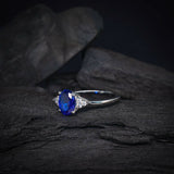 Anillo de compromiso con cristal azul y cristales laterales elaborado en oro blanco de 14 kilates