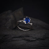 Anillo de compromiso con cristal azul y cristales laterales elaborado en oro blanco de 14 kilates