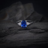 Anillo de compromiso con cristal azul y cristales laterales elaborado en oro blanco de 14 kilates