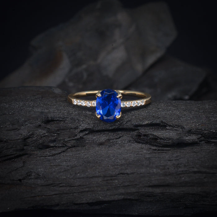 Anillo de compromiso con cristal azul y cristales laterales elaborado en oro amarillo de 14 kilates