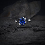 Anillo de compromiso con cristal azul y cristales laterales elaborado en oro blanco de 14 kilates