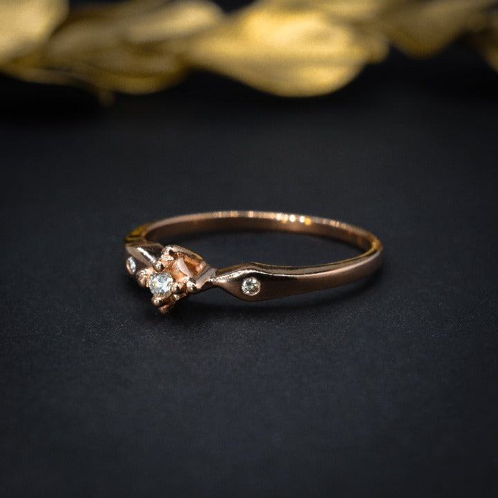 Anillo de compromiso con diamante natural de .04ct y 2 diamantes laterales elaborado en oro rosa de 14 kilates