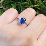 Anillo de compromiso con cristal azul y cristales laterales elaborado en oro blanco de 14 kilates