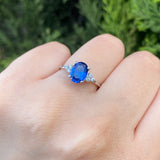 Anillo de compromiso con cristal azul y cristales laterales elaborado en oro blanco de 14 kilates