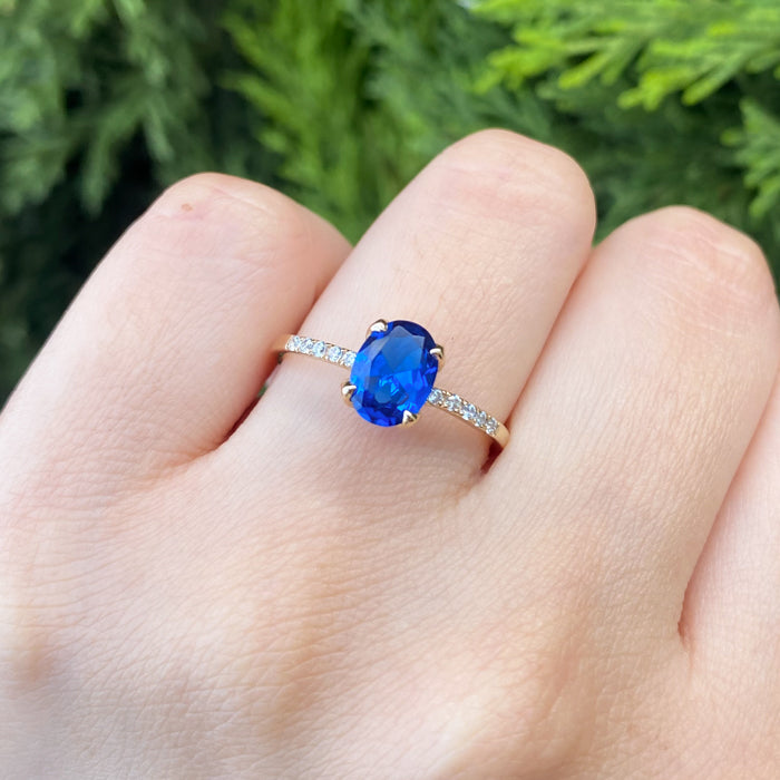 Anillo de compromiso con cristal azul y cristales laterales elaborado en oro amarillo de 14 kilates