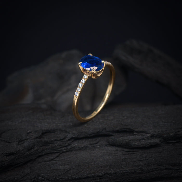 Anillo de compromiso con cristal azul y cristales laterales elaborado en oro amarillo de 14 kilates