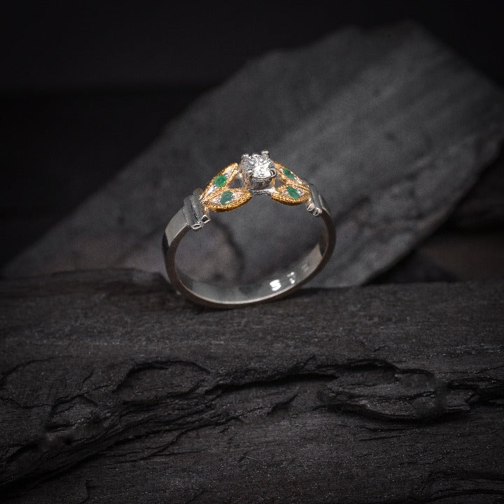 Anillo de compromiso con diamante natural de .15ct y esmeraldas laterales elaborado en oro amarillo y blanco de 14 kilates