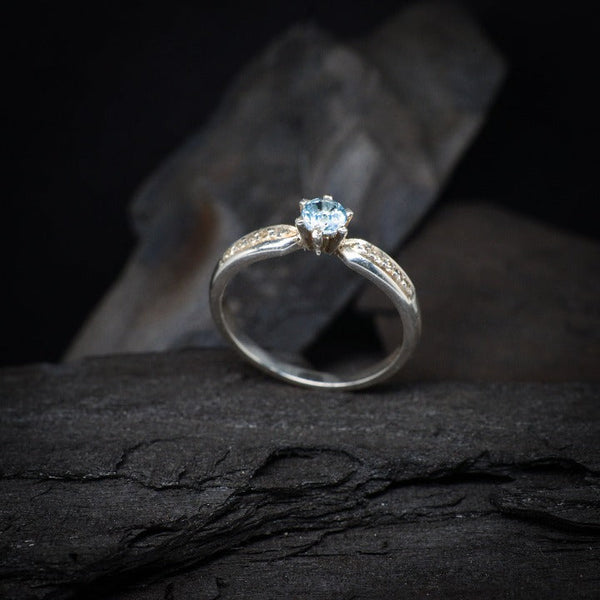 Anillo de compromiso con topacio natural y cristales laterales realizado en oro blanco de 14 kilates