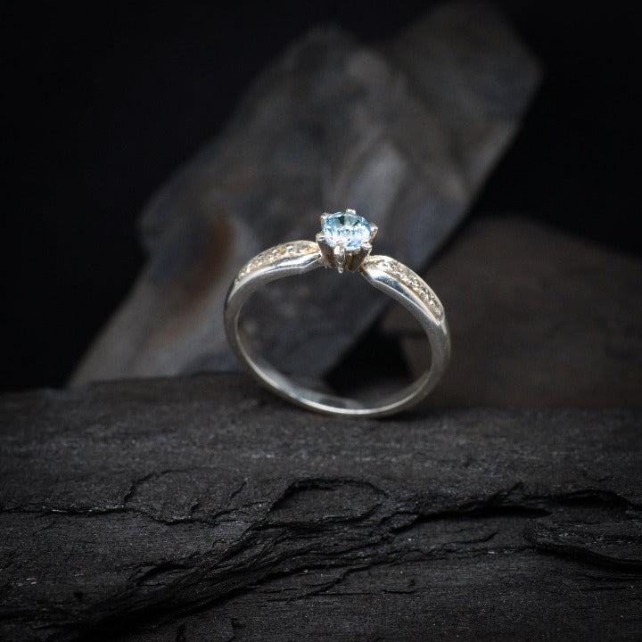 Anillo de compromiso con topacio natural y cristales laterales realizado en oro blanco de 14 kilates