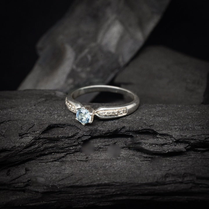 Anillo de compromiso con topacio natural y cristales laterales realizado en oro blanco de 14 kilates