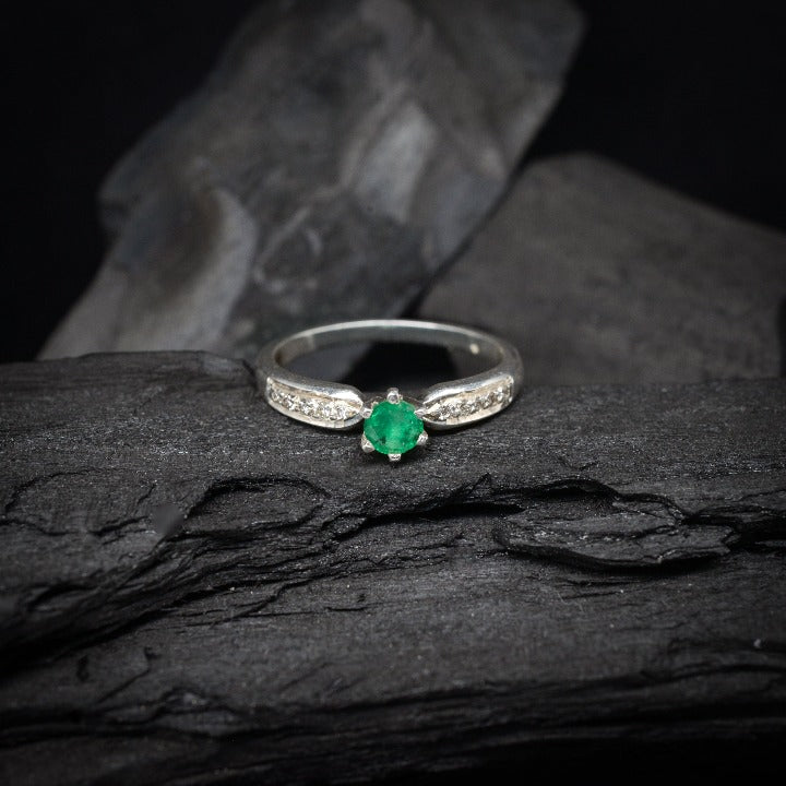 Anillo de compromiso con esmeralda natural y 10 diamantes laterales realizado en oro blanco de 14 kilates