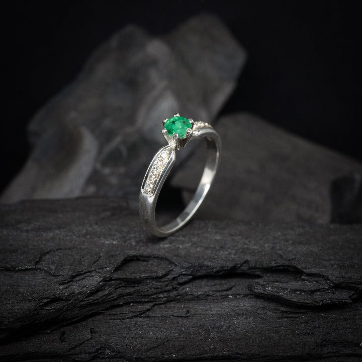 Anillo de compromiso con esmeralda natural y 10 diamantes laterales realizado en oro blanco de 14 kilates