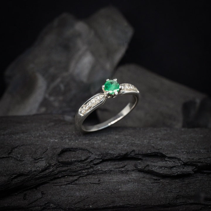 Anillo de compromiso con esmeralda natural y 10 diamantes laterales realizado en oro blanco de 14 kilates