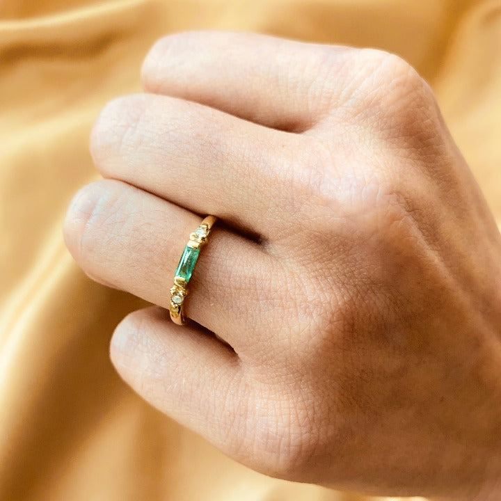 Anillo de compromiso con esmeralda natural de .15ct y 2 diamantes laterales elaborado en oro amarillo de 14 kilates