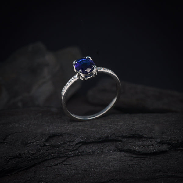 Anillo de compromiso con cristal azul y cristales laterales elaborado en oro blanco de 14 kilates