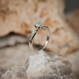 Anillo de compromiso con topacio natural y cristales laterales realizado en oro blanco de 14 kilates